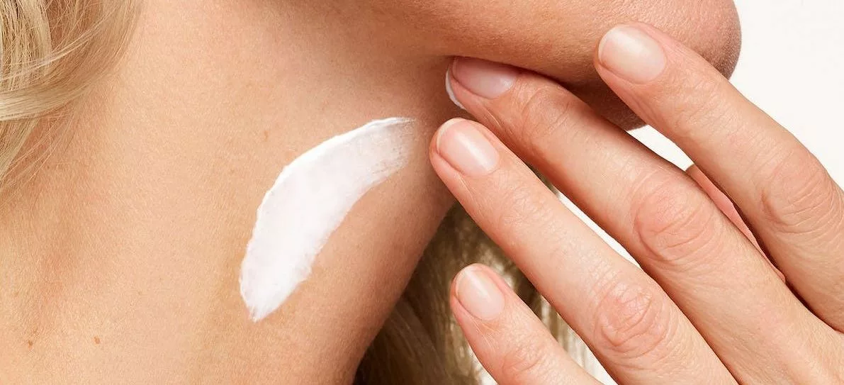 womans hands putting on neck cream