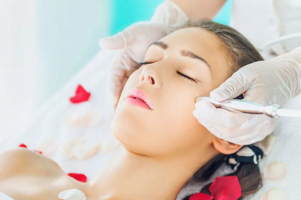 young womans face receiving facial treatment