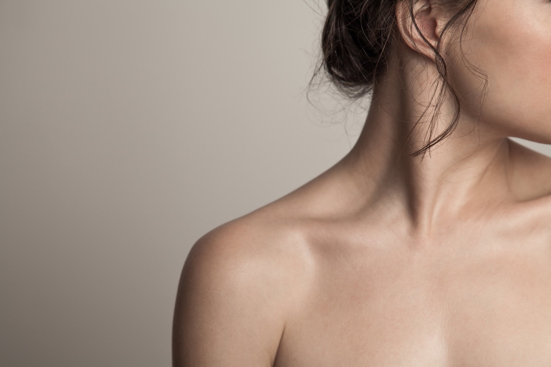Close-up of a woman's bare shoulder and jawline in soft natural light